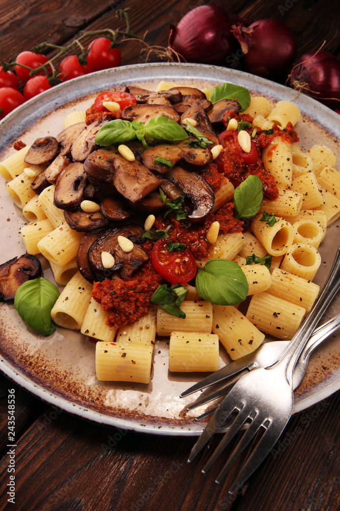 Penne pasta rigatoni in tomato sauce with mushrooms, tomatoes decorated with parsley and basil