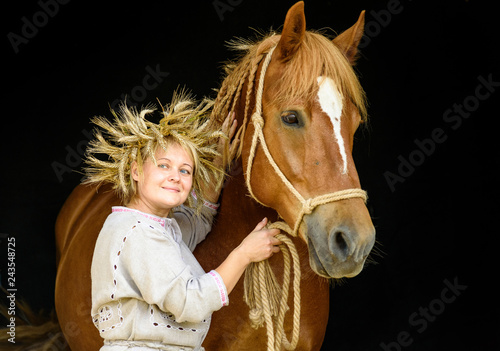 Portrait of a rural woman next to a horse against a dark background.