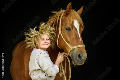 Portrait of a rural woman next to a horse against a dark background.