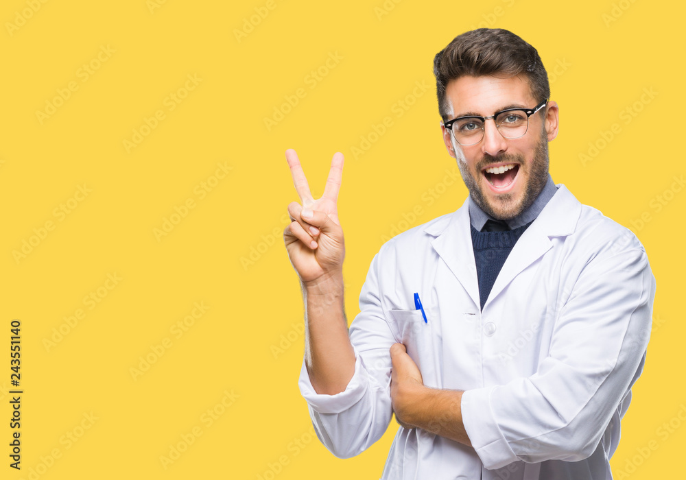 Young handsome man wearing doctor, scientis coat over isolated background smiling with happy face winking at the camera doing victory sign. Number two. Young handsome man wearing doctor, scientis coat over isolated background smiling with happy face winking at the camera doing victory sign. Number two.