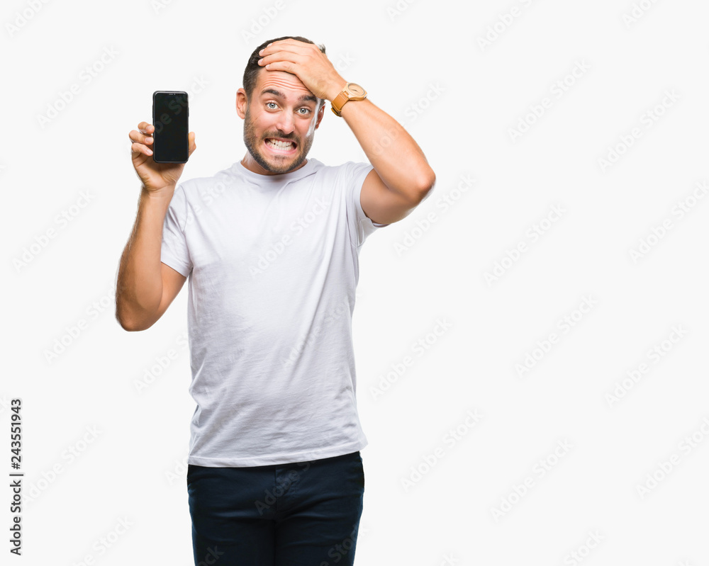 Young handsome man showing smartphone screen over isolated background stressed with hand on head, shocked with shame and surprise face, angry and frustrated. Fear and upset for mistake.