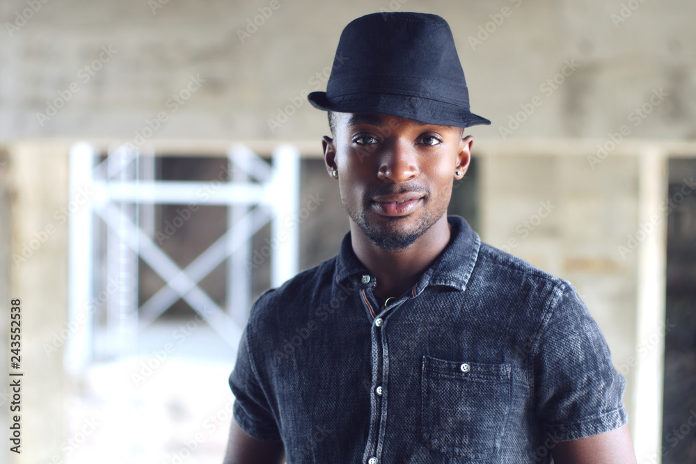 man with black shirt outside young african earings and hat portrait man with black shirt outside young african earings and hat portrait
