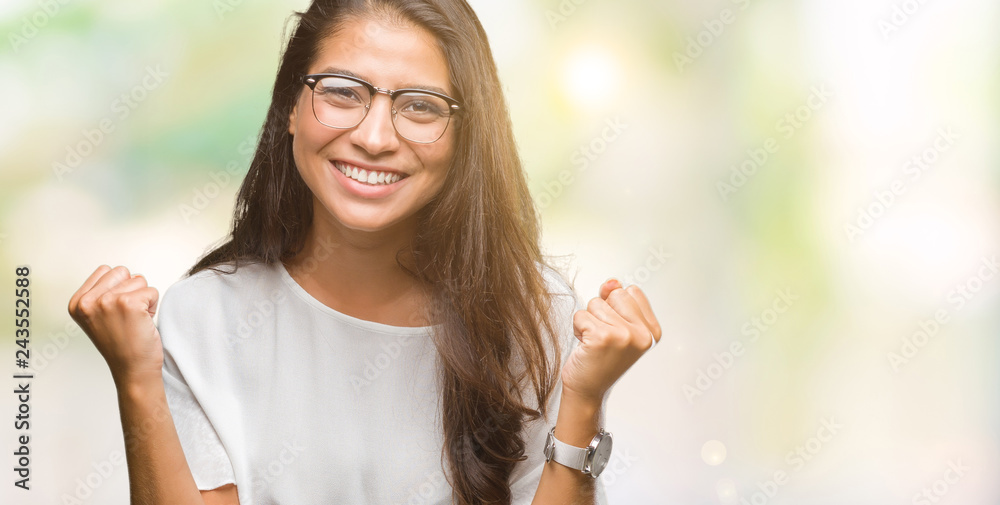 Young beautiful arab woman wearing glasses over isolated background celebrating surprised and amazed for success with arms raised and open eyes. Winner concept. Young beautiful arab woman wearing glasses over isolated background celebrating surprised and amazed for success with arms raised and open eyes. Winner concept.
