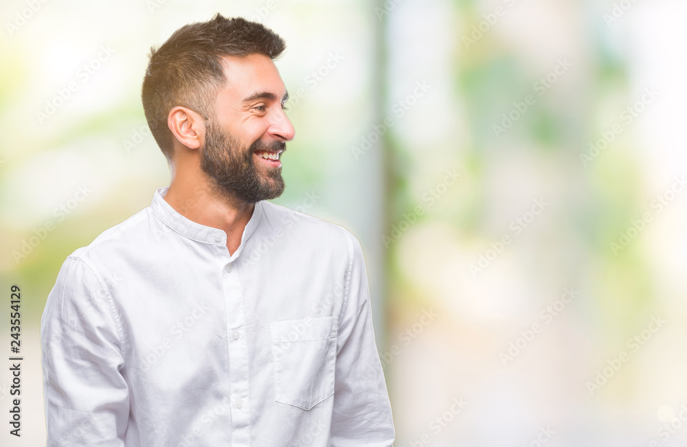 Naklejka premium Adult hispanic man over isolated background looking away to side with smile on face, natural expression. Laughing confident.