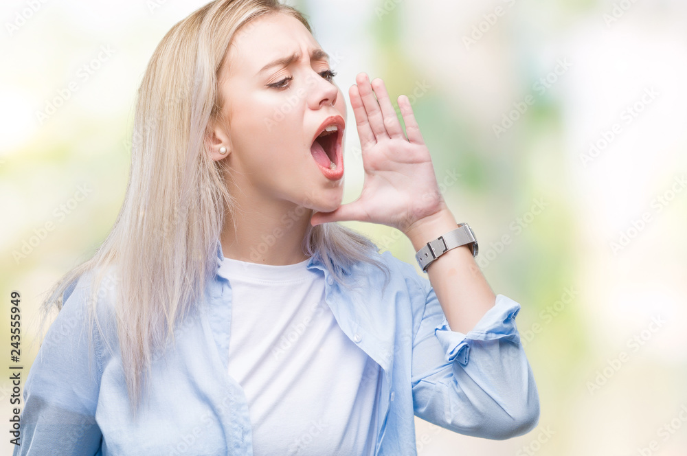 Young blonde woman over isolated background shouting and screaming loud to side with hand on mouth. Communication concept. Young blonde woman over isolated background shouting and screaming loud to side with hand on mouth. Communication concept.