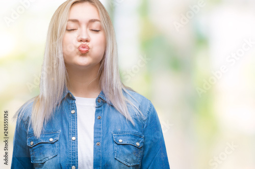 Young blonde woman over isolated background puffing cheeks with funny face. Mouth inflated with air, crazy expression.