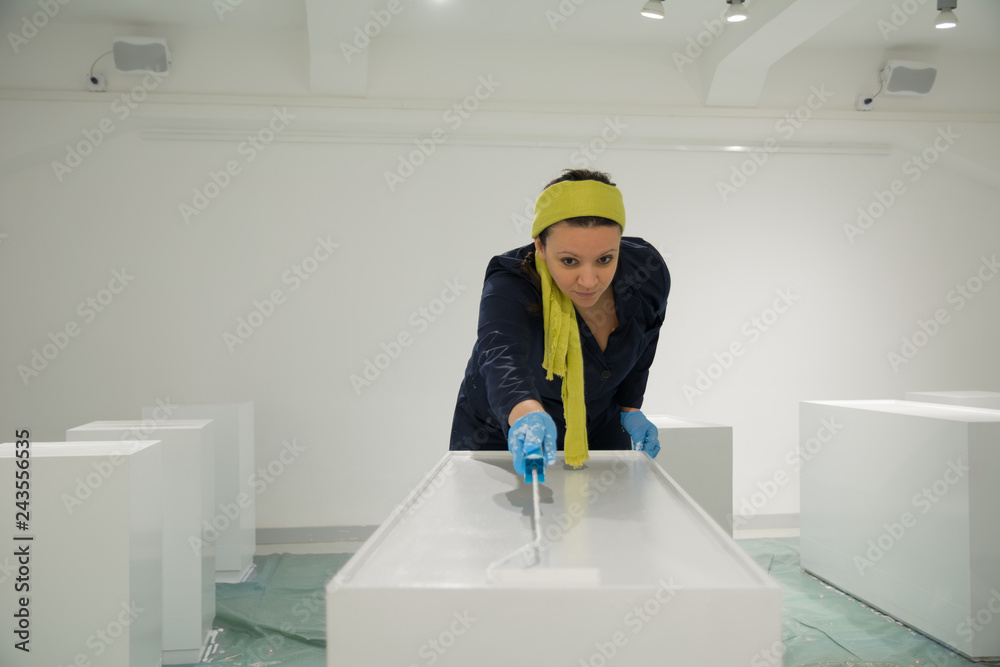 Women leaning over the furniture and paint it with a roller Women leaning over the furniture and paint it with a roller