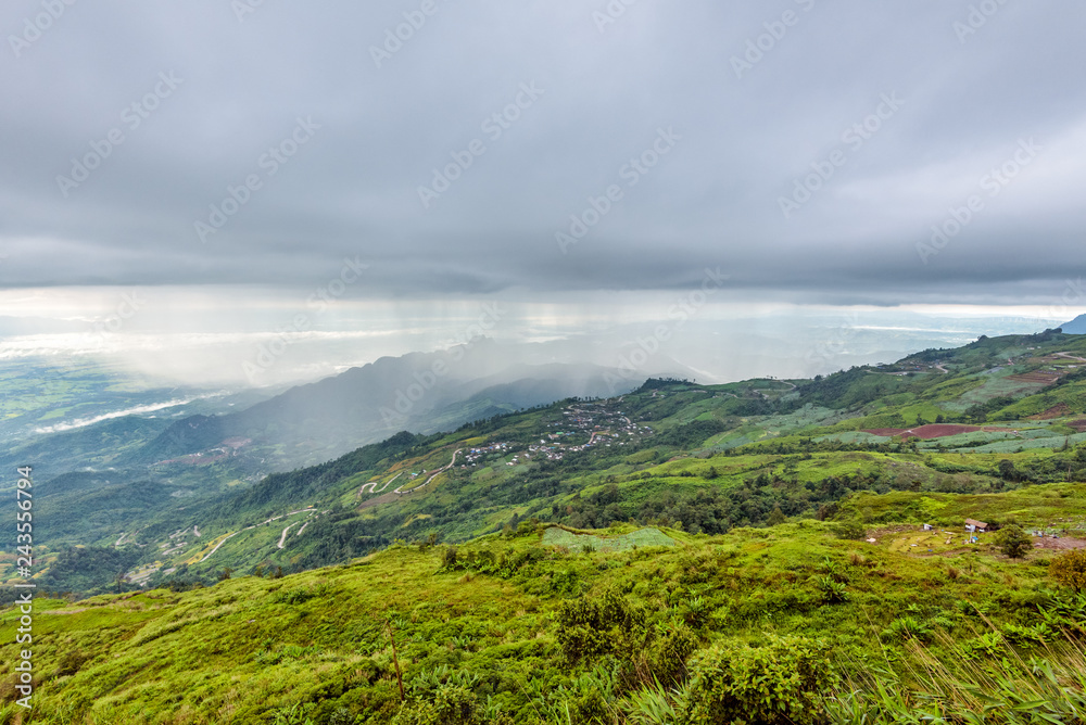 High view beautiful nature landscape of the mountain forest cloud and the rain is falling on the road through the rural village, way up to the Phu Thap Berk viewpoint, Phetchabun, Thailand
