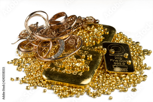 A pile of gold bars, gold jewelry and gold granules. Isolated on white background. Selective focus.