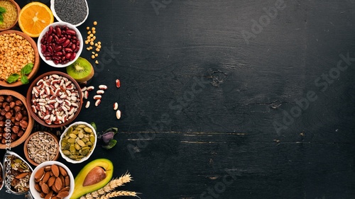 Various superfoods. Dried fruits  nuts  beans  fruits and vegetables. On a black wooden background. Top view. Free copy space.