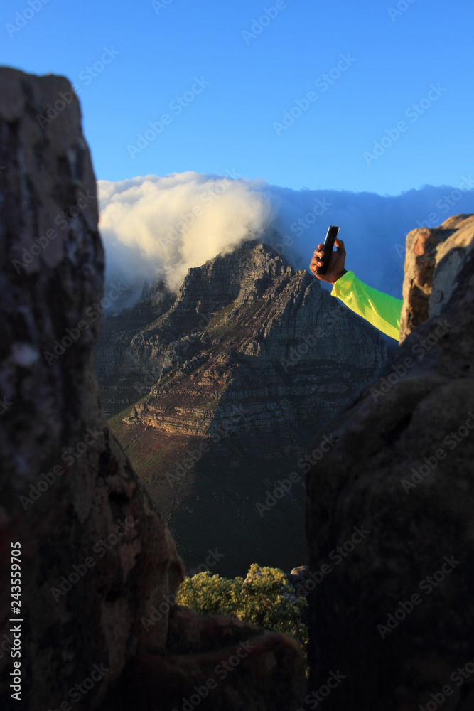 view of Table Mountain with clouds and hand taking selfie