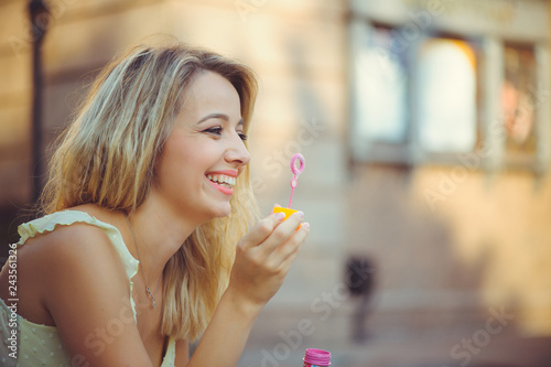 Beauty girl with colorful soap bubbles laughing. Beautiful happy young woman on a sunny bright day. Joyful model plays with soap bubbles on a beautiful day