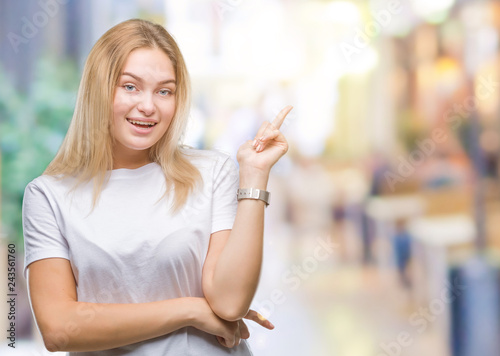 Young caucasian woman over isolated background with a big smile on face, pointing with hand and finger to the side looking at the camera.