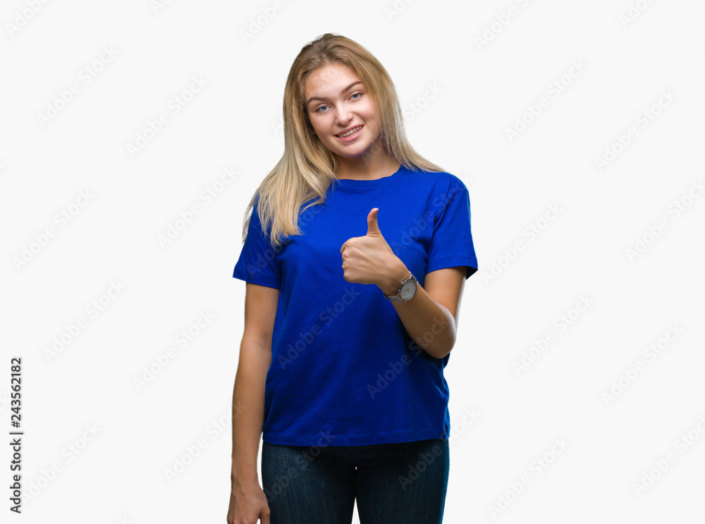 Young caucasian woman over isolated background doing happy thumbs up gesture with hand. Approving expression looking at the camera with showing success.