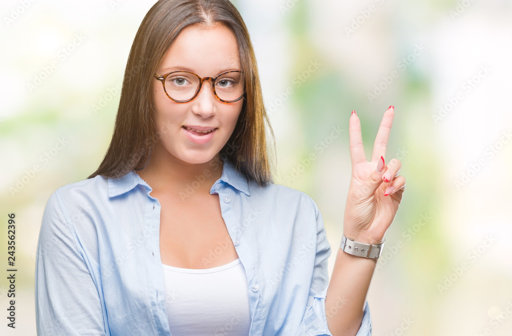 Young caucasian beautiful business woman wearing glasses over isolated background smiling with happy face winking at the camera doing victory sign. Number two. Young caucasian beautiful business woman wearing glasses over isolated background smiling with happy face winking at the camera doing victory sign. Number two.