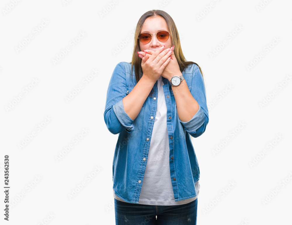 Young beautiful caucasian woman wearing sunglasses over isolated background shocked covering mouth with hands for mistake. Secret concept. Young beautiful caucasian woman wearing sunglasses over isolated background shocked covering mouth with hands for mistake. Secret concept.