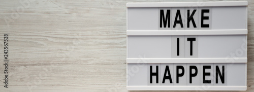 Modern board with text 'Make it happen'on a white wooden surface, top view. From above, flat lay, overhead. photo