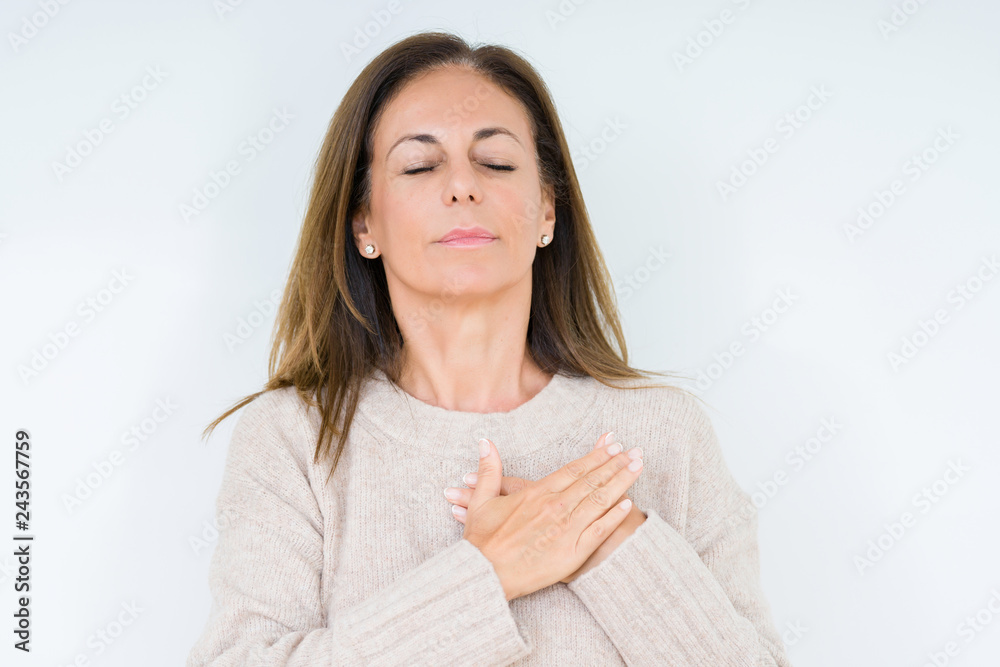 Beautiful middle age woman over isolated background smiling with hands on chest with closed eyes and grateful gesture on face. Health concept. Beautiful middle age woman over isolated background smiling with hands on chest with closed eyes and grateful gesture on face. Health concept.