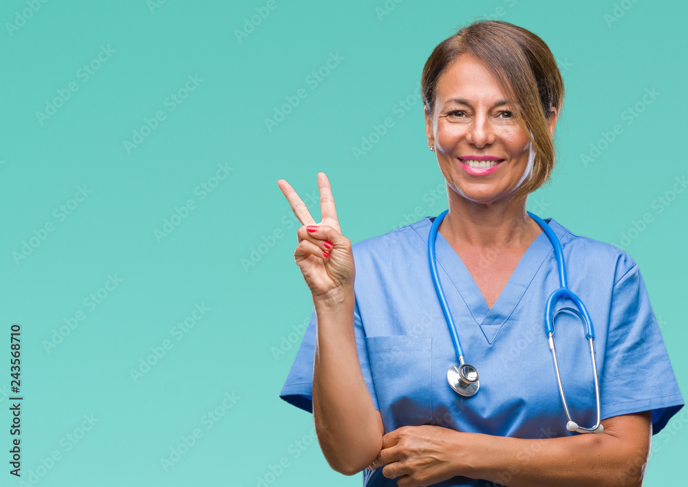 Middle age senior nurse doctor woman over isolated background smiling with happy face winking at the camera doing victory sign. Number two. Middle age senior nurse doctor woman over isolated background smiling with happy face winking at the camera doing victory sign. Number two.