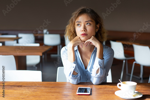 Obraz na plátně Serious businesswoman with curly hair sitting in coffee shop