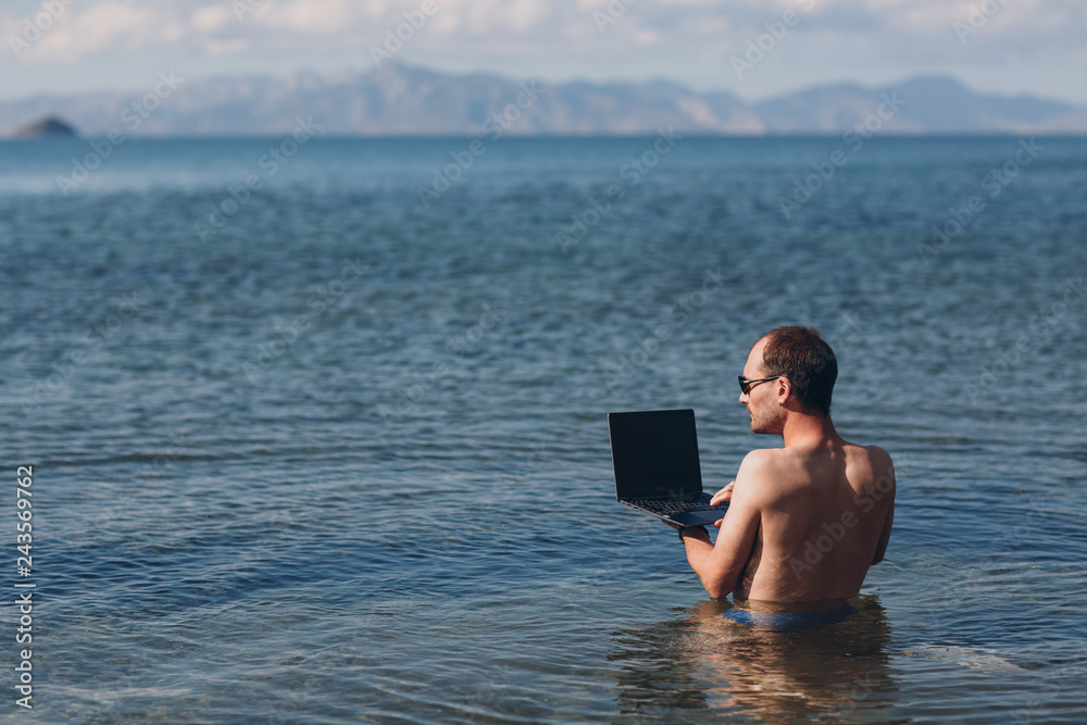 Young businessman works with a laptop by the sea