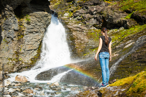 Young woman next to Waterfall in the Geiranger valley near Dalsnibba mountain, Norway