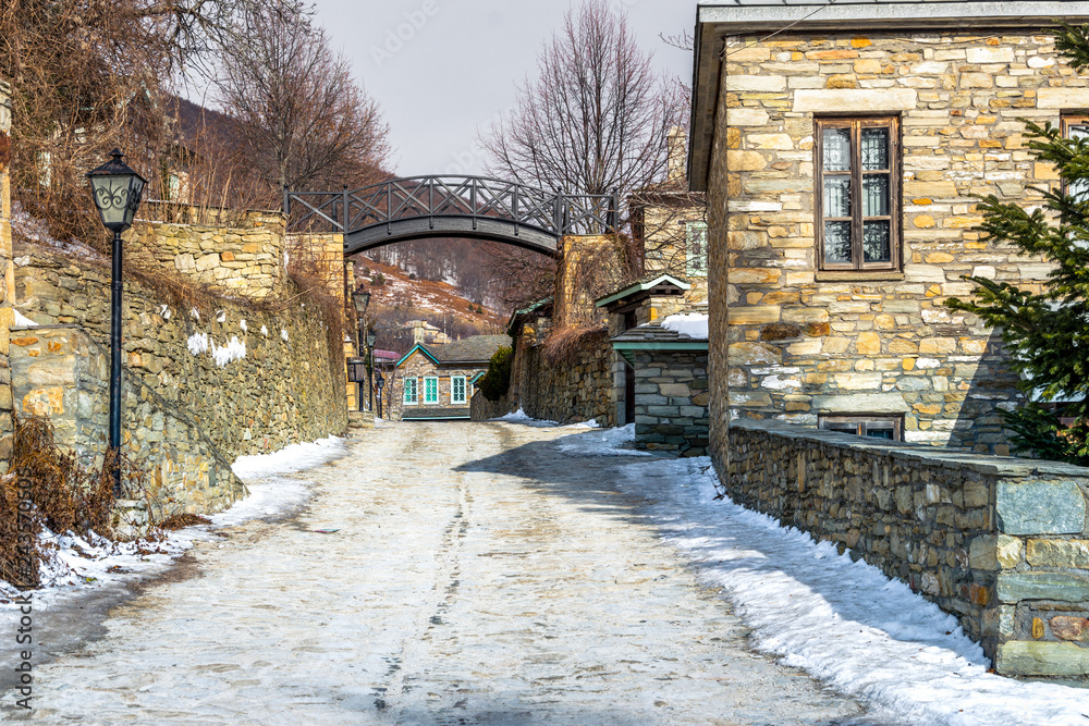 Fototapeta premium View of traditional stone buildings and streets with snow at the famous village of Nymfaio near Florina, Greece. 