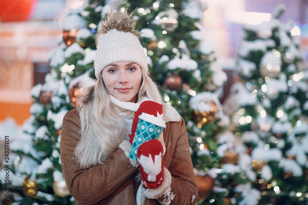 Young smiling female with a coffee cup on the winter new year street Young smiling female with a coffee cup on the winter new year street