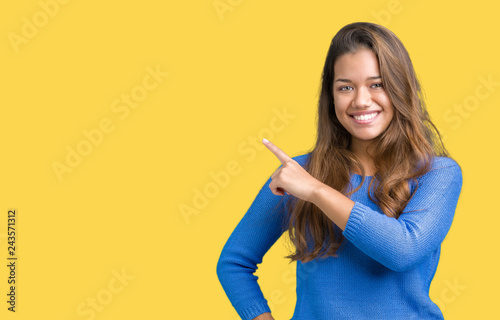 Young beautiful brunette woman wearing blue sweater over isolated background Pointing with hand finger to the side showing advertisement  serious and calm face