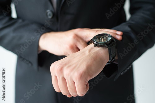 Businessman consulting wristwatch. Cropped portrait of business leader checking time. Time management concept
