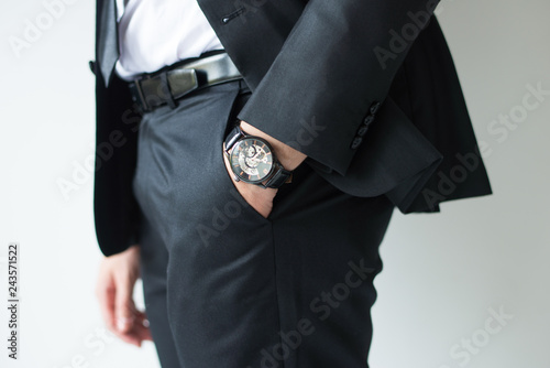Closeup of watch on businessman wrist. Business leader hand slipping in pocket. Business accessory concept