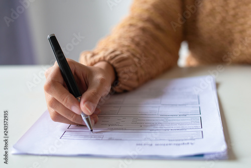 Close-up of lady filling application form. Unrecognizable woman in sweater sitting at table and preparing her resume. Job search concept photo
