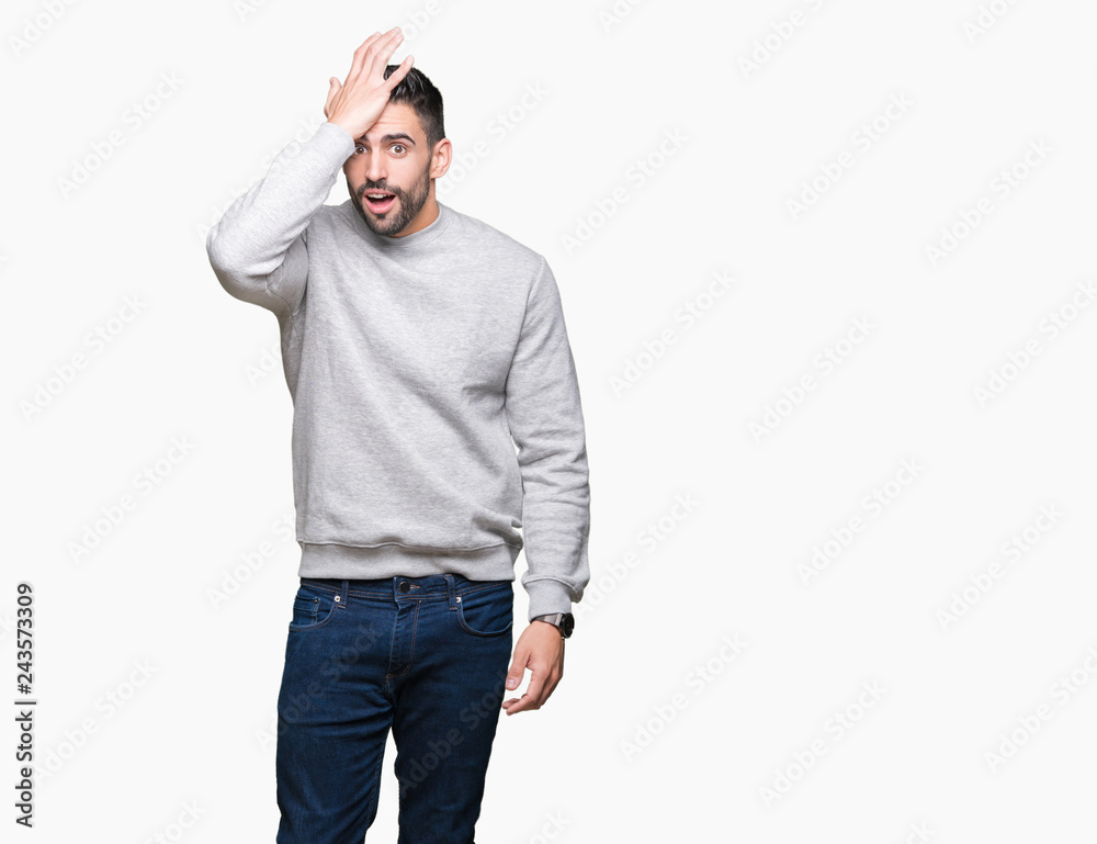 Fototapeta premium Young handsome man wearing sweatshirt over isolated background surprised with hand on head for mistake, remember error. Forgot, bad memory concept.