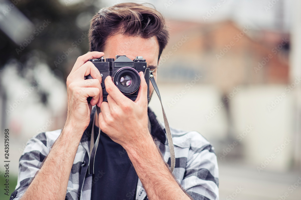 Young attractive man, a photographer, taking photographs in an urban area with an analog SLR camera Young attractive man, a photographer, taking photographs in an urban area with an analog SLR camera