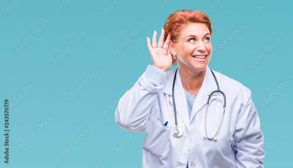 Senior caucasian doctor woman wearing medical uniform over isolated background smiling with hand over ear listening an hearing to rumor or gossip. Deafness concept. Senior caucasian doctor woman wearing medical uniform over isolated background smiling with hand over ear listening an hearing to rumor or gossip. Deafness concept.