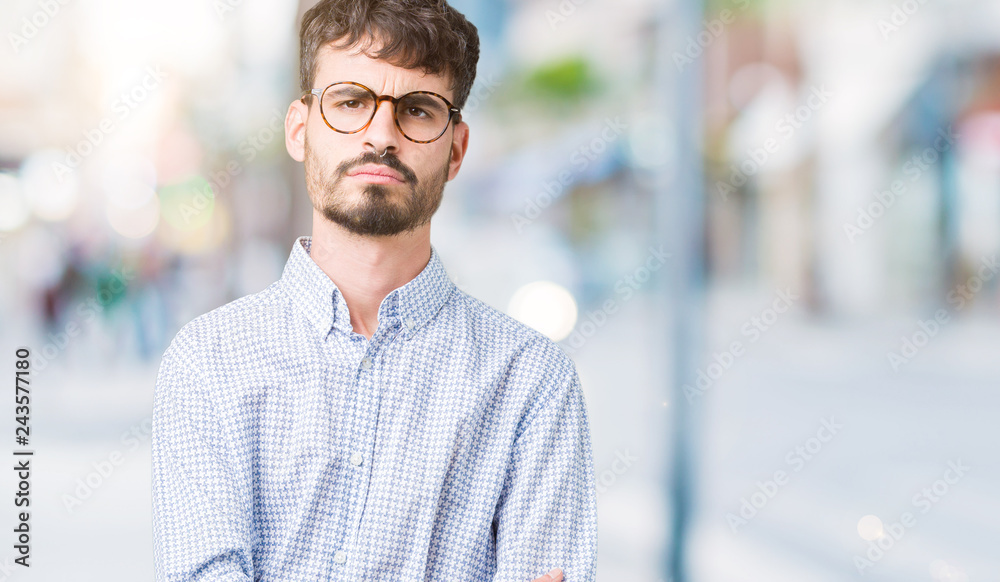 Young handsome man wearing glasses over isolated background skeptic and nervous, disapproving expression on face with crossed arms. Negative person. Young handsome man wearing glasses over isolated background skeptic and nervous, disapproving expression on face with crossed arms. Negative person.