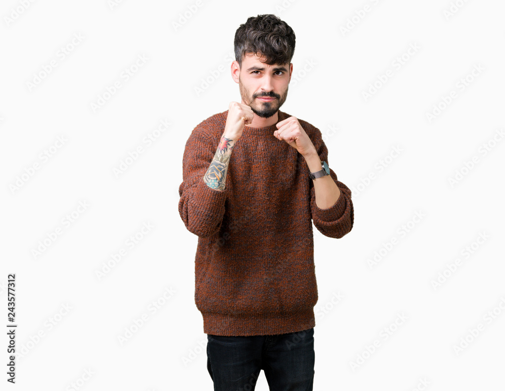 Young handsome man wearing winter sweater over isolated background Ready to fight with fist defense gesture, angry and upset face, afraid of problem Young handsome man wearing winter sweater over isolated background Ready to fight with fist defense gesture, angry and upset face, afraid of problem