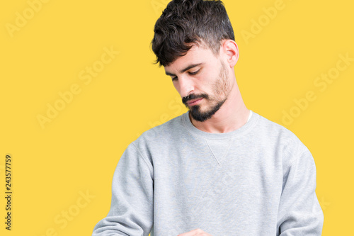 Young handsome man wearing sweatshirt over isolated background Checking the time on wrist watch, relaxed and confident