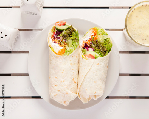 Vegan wrap, top down view -  Beautifully arranged and surved on a white wooden table