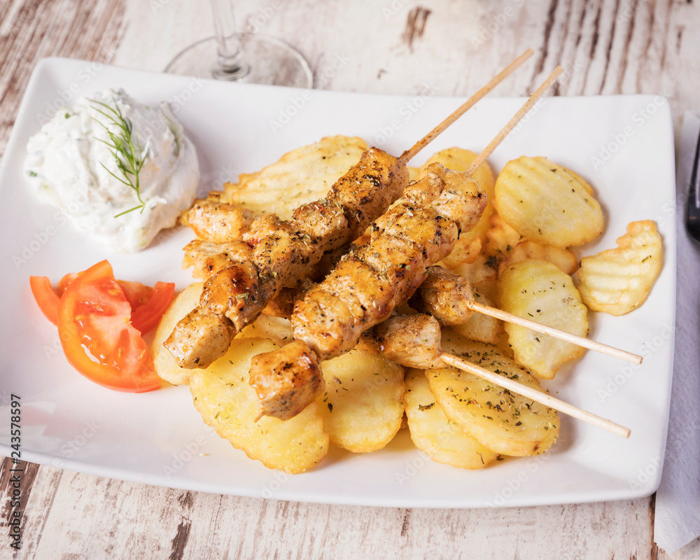 Greek food, chicken skewer - Delicious mediterranean chicken meat with grilled potatoes, beautifully arranged dinner on a white table Greek food, chicken skewer - Delicious mediterranean chicken meat with grilled potatoes, beautifully arranged dinner on a white table
