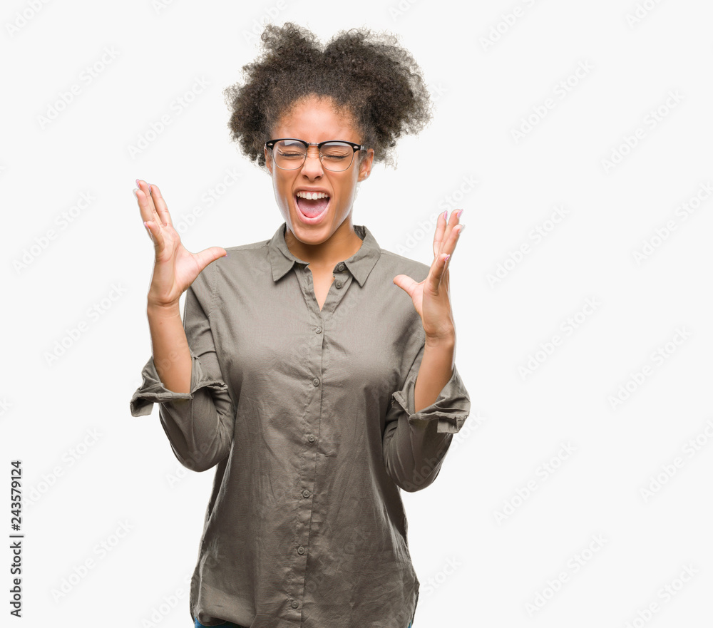 Young afro american woman wearing glasses over isolated background celebrating mad and crazy for success with arms raised and closed eyes screaming excited. Winner concept Young afro american woman wearing glasses over isolated background celebrating mad and crazy for success with arms raised and closed eyes screaming excited. Winner concept