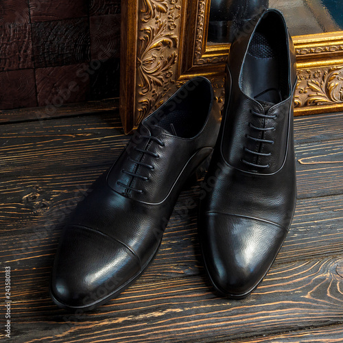 Classic male black leather shoes on wooden background