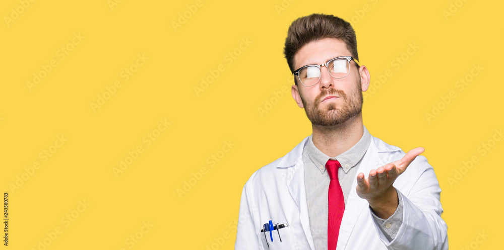 Young handsome scientist man wearing glasses looking at the camera blowing a kiss with hand on air being lovely and sexy. Love expression. Young handsome scientist man wearing glasses looking at the camera blowing a kiss with hand on air being lovely and sexy. Love expression.
