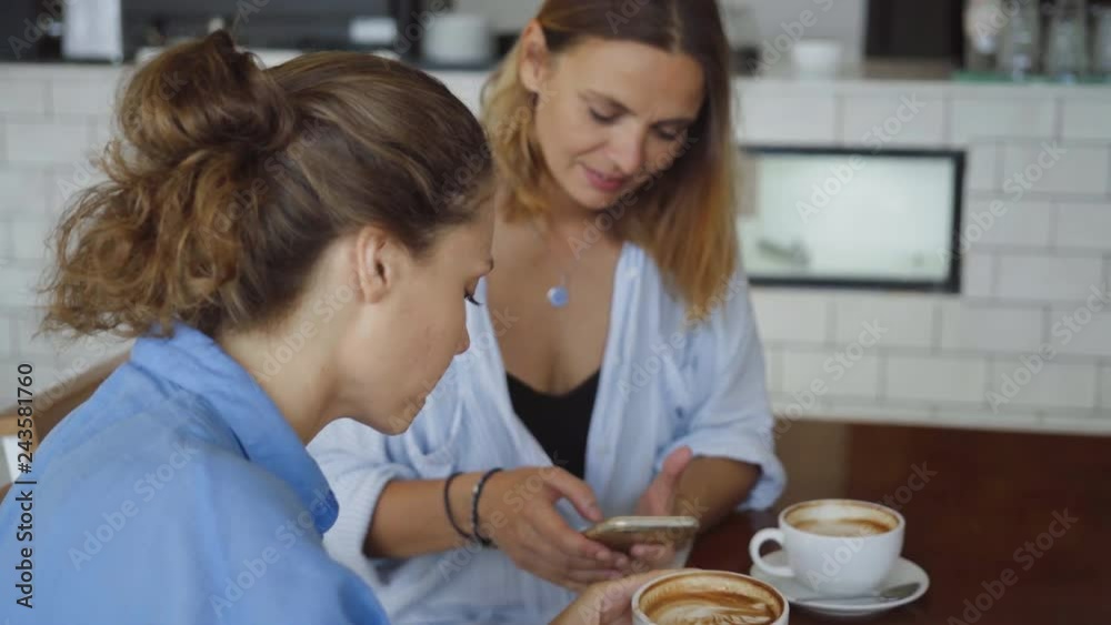 Women having date in cafe. One Sharing something Exciting on her Mobile Phone Women having date in cafe. One Sharing something Exciting on her Mobile Phone
