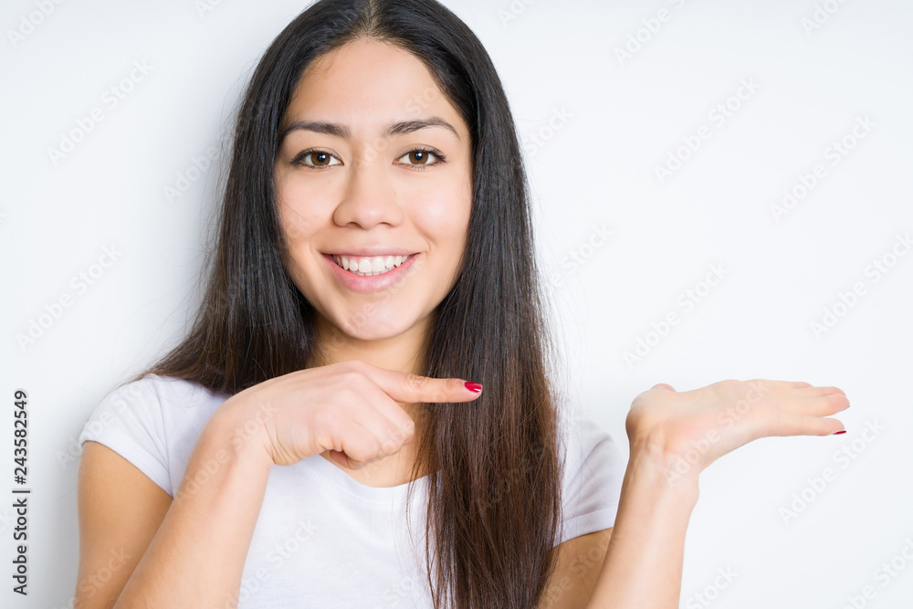 Beautiful brunette woman over isolated background amazed and smiling to the camera while presenting with hand and pointing with finger. Beautiful brunette woman over isolated background amazed and smiling to the camera while presenting with hand and pointing with finger.