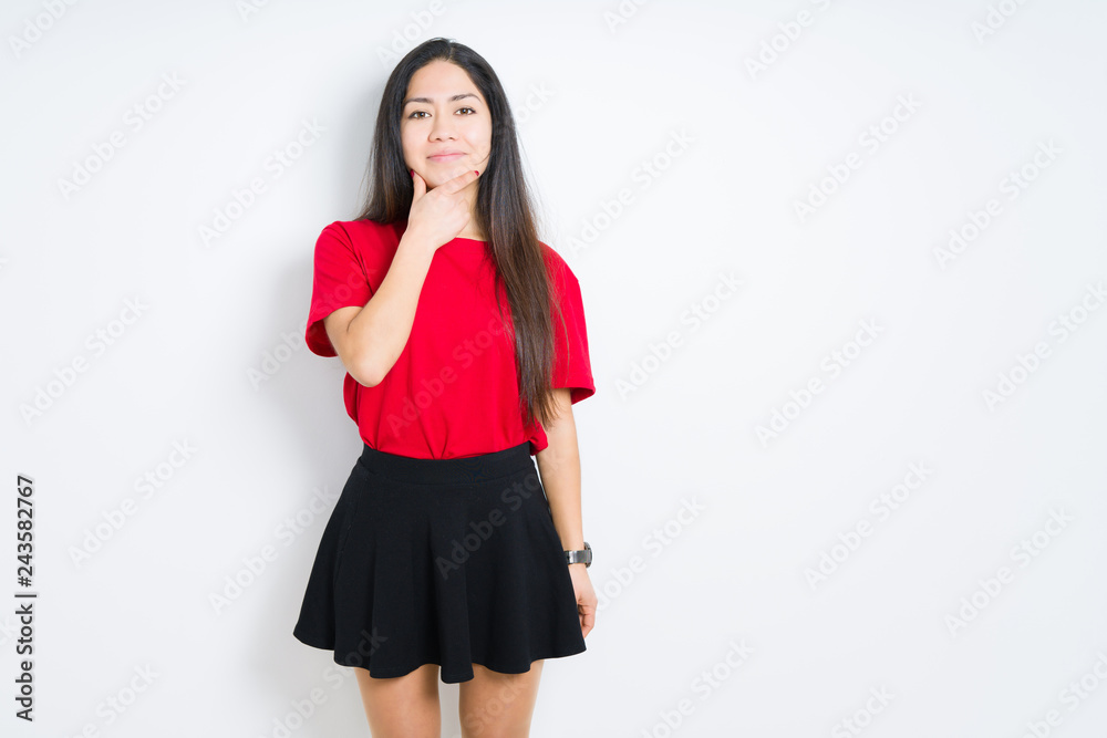 Beautiful brunette woman wearing red t-shirt and skirt over isolated background looking confident at the camera with smile with crossed arms and hand raised on chin. Thinking positive. Beautiful brunette woman wearing red t-shirt and skirt over isolated background looking confident at the camera with smile with crossed arms and hand raised on chin. Thinking positive.