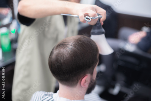 The hairdresser is doing his job. Scissor cutting.