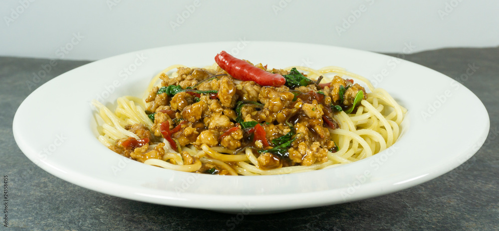 Spaghetti Fried Stir Basil with Minced pork in a dish white on a black stone floor table,food concept..