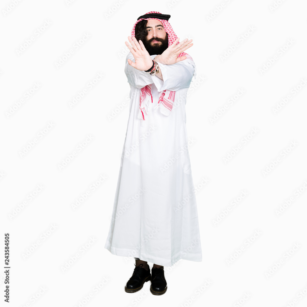 Arabian business man with long hair wearing traditional keffiyeh scarf Rejection expression crossing arms and palms doing negative sign, angry face Arabian business man with long hair wearing traditional keffiyeh scarf Rejection expression crossing arms and palms doing negative sign, angry face