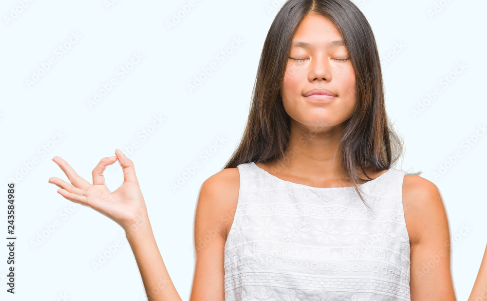 Young asian woman over isolated background relax and smiling with eyes closed doing meditation gesture with fingers. Yoga concept. Young asian woman over isolated background relax and smiling with eyes closed doing meditation gesture with fingers. Yoga concept.